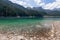 Ð¡rystal clear emerald water of Tovel lake in frame of stony shore and Italian Alps covered with forest and snow,Â Ville Anauni